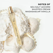 Vanilla Salt 10ml Eau De Parfum Travel Spray resting on whipped cream, vanilla ice cream, and pearl necklace, on white background next to black text that reads 