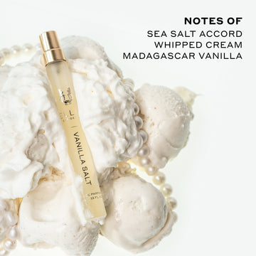 Vanilla Salt 10ml Eau De Parfum Travel Spray resting on whipped cream, vanilla ice cream, and pearl necklace, on white background next to black text that reads "Notes Of Sea Salt Accord, Whipped Cream, Madagascar Vanilla".