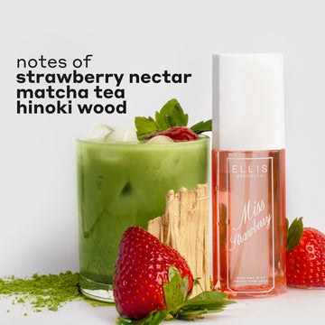 MISS STRAWBERRY Perfume Mist 90ml next to matcha powder, two strawberries, hinoki wood, and a glass cup filled with ice, matcha tea, and a strawberry with black text that reads "notes of strawberry nectar, matcha tea, hinoki wood" on a white background