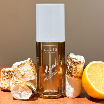 MARSHMALLOWS Perfume Mist 240ml between half a lemon and tosted marshmallows on wooden surface with a tan bakground