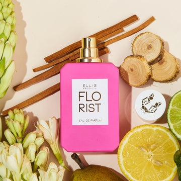 Florist 50 ml Eau de Parfum avec le bouchon retiré sur un fond rose pâle avec citron, lime, bois de santal, poire, fleurs et bois de cèdre