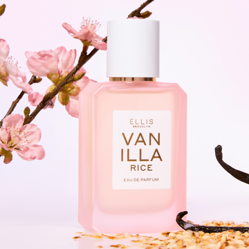 VANILLA RICE Eau de Parfum 50ml next to toasted rice, vanilla beans, and pink sakura blossoms on a pink background 