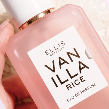 Closeup of hand holding VANILLA RICE Eau de Parfum 50ml with rice in the background