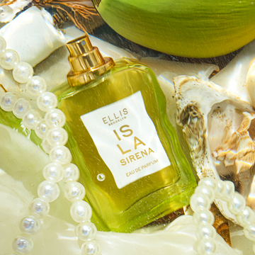 ISLA SIRENA Eau de Parfum 50ml without cap sits on white fabric next to white pearls, a white shell, and a green coconut all under water
