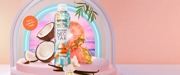 Amika x Ellis Brooklyn Miami Nectar Perk Up Dry Shampoo on pink pedestal with vanilla beans, coconut, pineapple, and flowers on white table against a neon arch and pink sunset and palm leaves, on pink background with orange circle with white text that reads "For a limited time!"