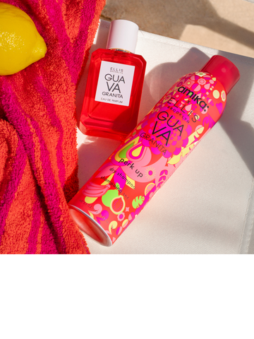 GUAVA GRANITA Eau de Parfum 50ml and Amika x Ellis Brooklyn GUAVA GRANITA Perk Up Dry Shampoo on white beach chair next to pink and orange beach towel and a lemon on a background of tan sand