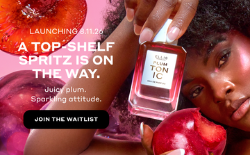Woman with brown hair wearing pink highlighter holds PLUM TONIC Eau de Parfum 50ml against her head in one hand and a plum with a bite out of it in the other hand on a pink background with sliced plums and white text that reads "Launching 8.11.26. A top-shelf spritz is on the way. Juicy plum. Sparkling attitude." and a black oval with white text that reads "Join The Waitlist"