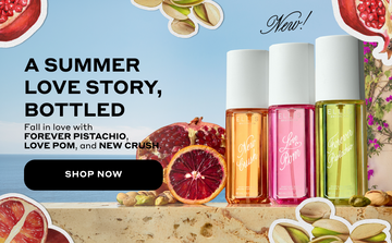 NEW CRUSH Perfume Mist 90ml, LOVE POM Perfume Mist 90ml, and FOREVER PISTACHIO Perfume Mist 90ml stand on tan marble next to a pomegranate, a blood orange, and pistachios in front of a tan wall with purple flowers, a blue ocean and sky with drawn images of pomegranate, sliced blood orange, and pistachios with a white outline with black text that reads "New! A Summer Love Story, Bottled. Fall in love with FOREVER PISTACHIO, LOVE POM, and NEW CRUSH." and a black oval with white text that reads "Shop Now"
