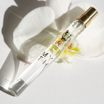 Myth 10ml Eau de Parfum vaporisateur de voyage posé sur une fleur d'orchidée blanche sur fond blanc.