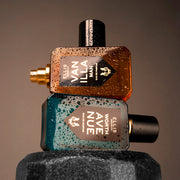 Vanilla Man 50ml Eau De Parfum with cap removed on top of Worth Avenue 50ml Eau De Pafum on top of dumbbell covered with wate droplettes, on brown background.