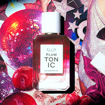 PLUM TONIC Eau de Parfum 50ml on collage of pink sequins, pink glittery stars, a pink disco ball, plums, a woman wearing a silver sequin dress and clutch, pink fabric, and a rose gold chain necklace