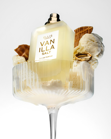 Vanilla Salt 50ml Eau De Parfum without cap in glass with vanilla ice cream, pieces of ice cream cone, and gold ring, on white background