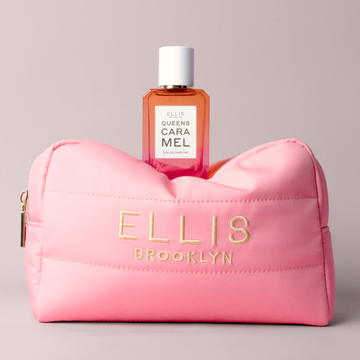 Pink Cosmetic Bag with gold embroidery that reads "Ellis Brooklyn" with QUEENS CARAMEL Eau de Parfum 50ml on top on gray background
