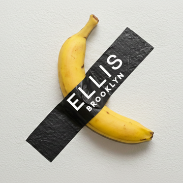 Banana taped to a gray wall with thick, black tape with white text that reads "Ellis Brooklyn" 