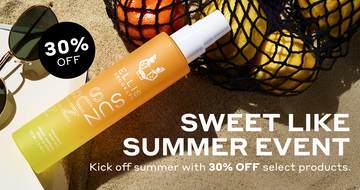 Sun Hair and Body Fragrance Mist 100ml in sand leaning on black mesh bag filled with oranges and lemons, and corner of open book, next to sunglasses, next tot black circle with white text that reads 
