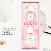 Ellis Brooklyn Twice as Nice gift set containing one 7.5mL mini-Vanilla Salt & 1 7.5mL mini-Vanilla Rice bottles in a pink floral window box packaging, styled with white orchid flowers and vanilla beans on a white background with promotional text in center left of background that reads 
