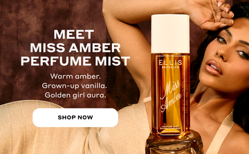 Miss Amber 240ml Perfume Mist bottle on amber rock in front of a model with brown hair wearing a tan dress, with white text reading 'MEET MISS AMBER PERFUME MIST. Warm amber. Grown-up vanilla. Golden girl aura.' and a white oval with black text that reads 'SHOP NOW' all on a brown background