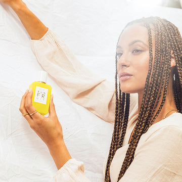 IMAGE 4: MODEL HOLDING SUN FRUIT 50ML BOTTLE AGAINST FABRIC
