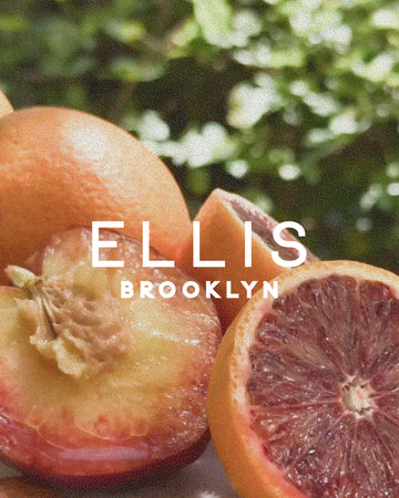 Sliced blood oranges and nectarines against green leaves with white text that reads "Ellis Brooklyn"