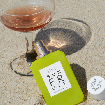 IMAGE 5: SUN FRUIT 50ML BOTTLE at beach in sand near drink 